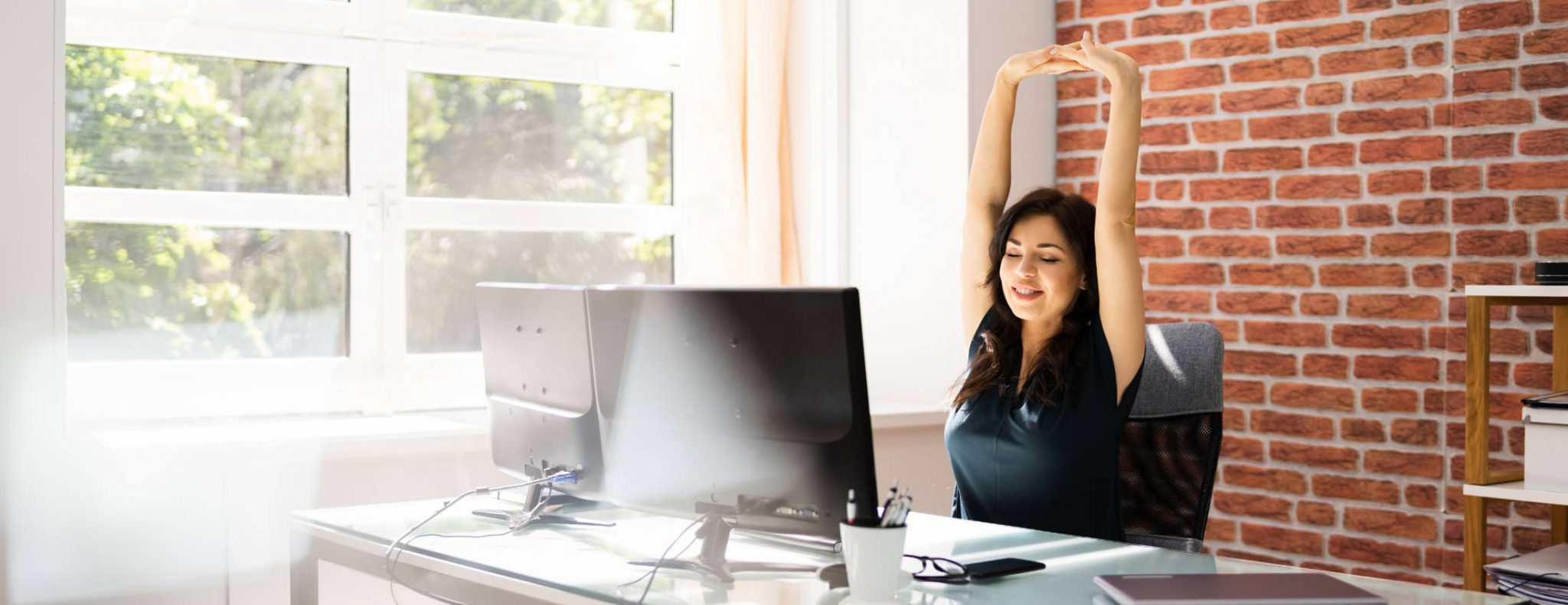 photo d'une employée de bureau qui fait des étirements pour éviter les risques physiques au travail