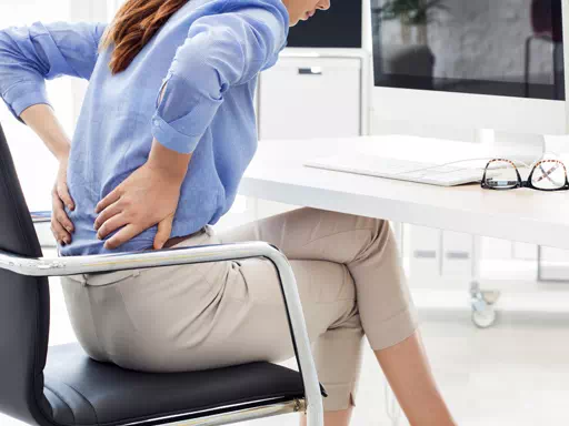 image d'une femme qui a mal au dos sur son fauteuil de bureau et qui devrait faire une formation risques physiques chez bernat conseil & formation