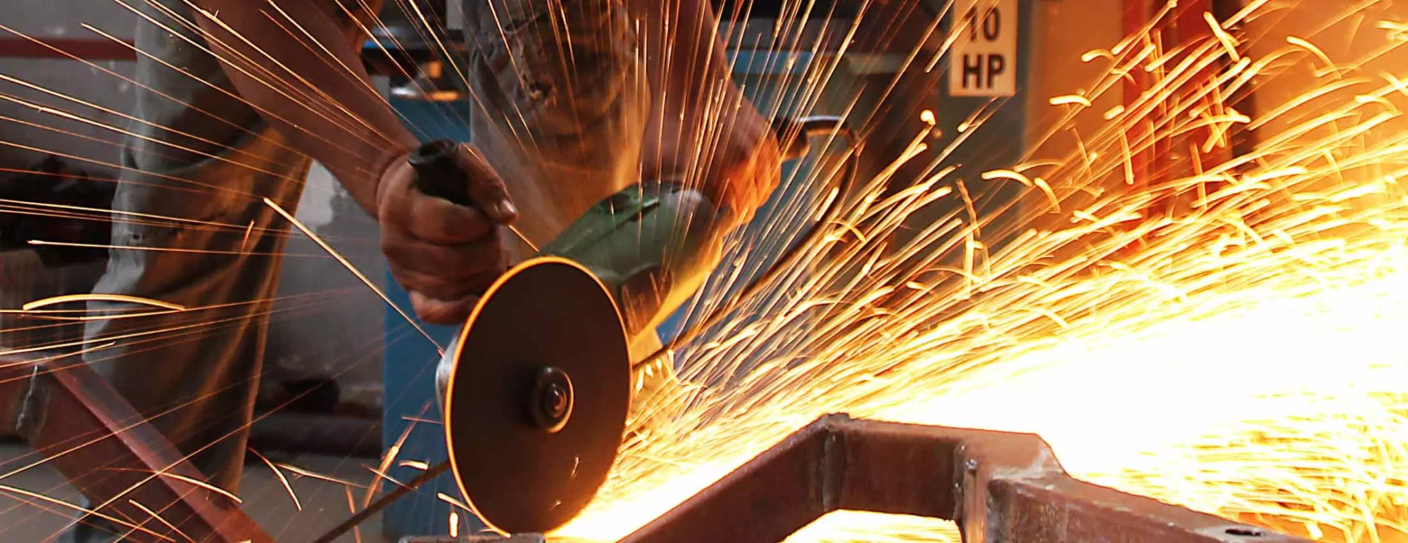 photo d'un ouvrier qui meule du fer et qui crée une gerbe d'étincelle dans une entreprise pour le permis de feu de bernat conseil et formation