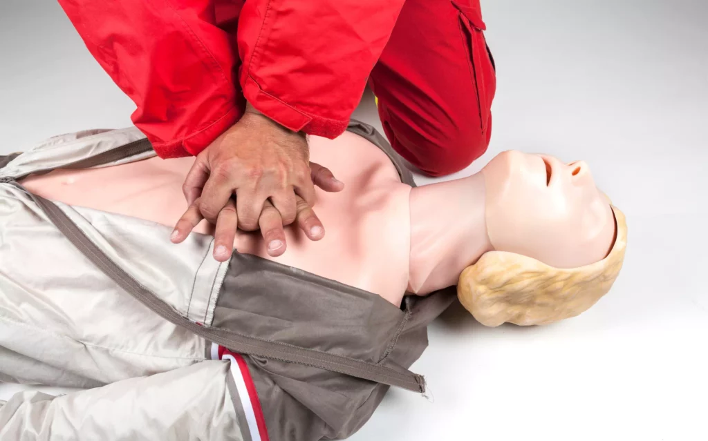 Un homme pratique un massage cardiaque sur un mannequin lors d'un formation SST recyclage.