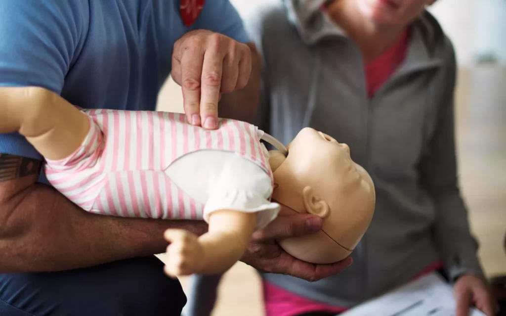 un homme s'entraine sur un mannequin nourrisson. cela illustre l'article la formation SST, c’est quoi ? Définition et contenu