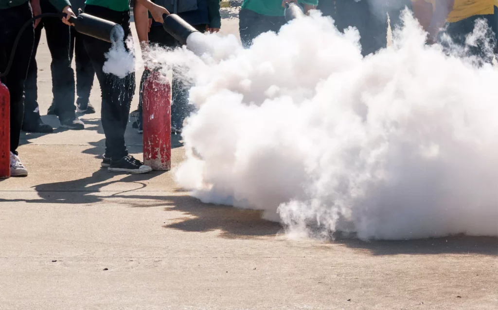 Lors d'une formation incendie obligatoire, un apprenant utilise un extincteur au CO2