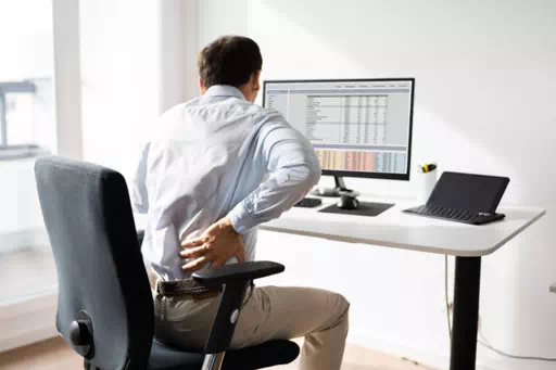Un homme devant son écran de PC qui a mal au dos suit une formation E-learning travail devant écran