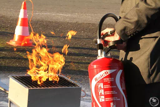 Un apprenant utilise un extincteur pour éteindre un bac à feu en formation équipier de première intervention